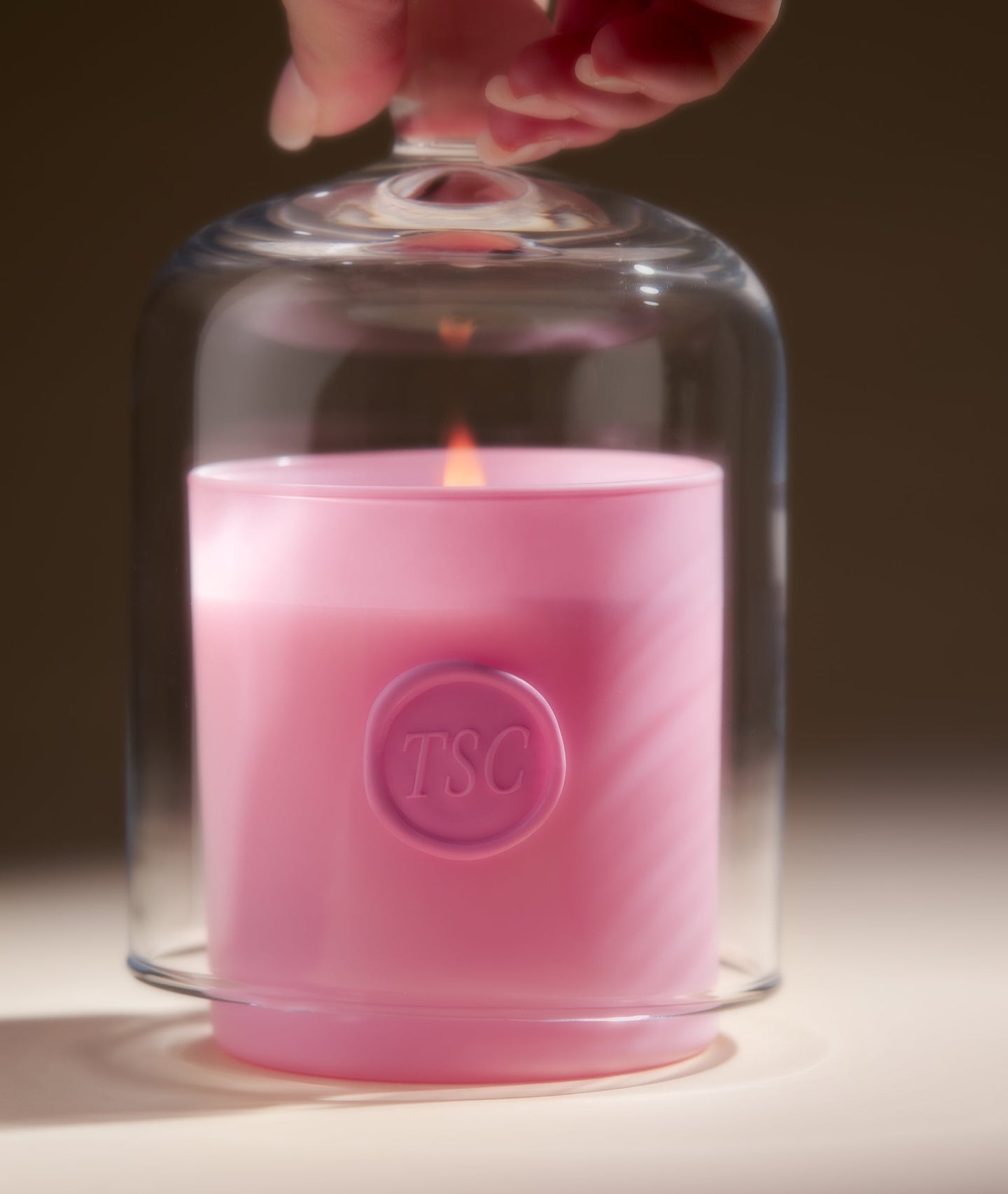 Pink candle under glass dome with flame.
