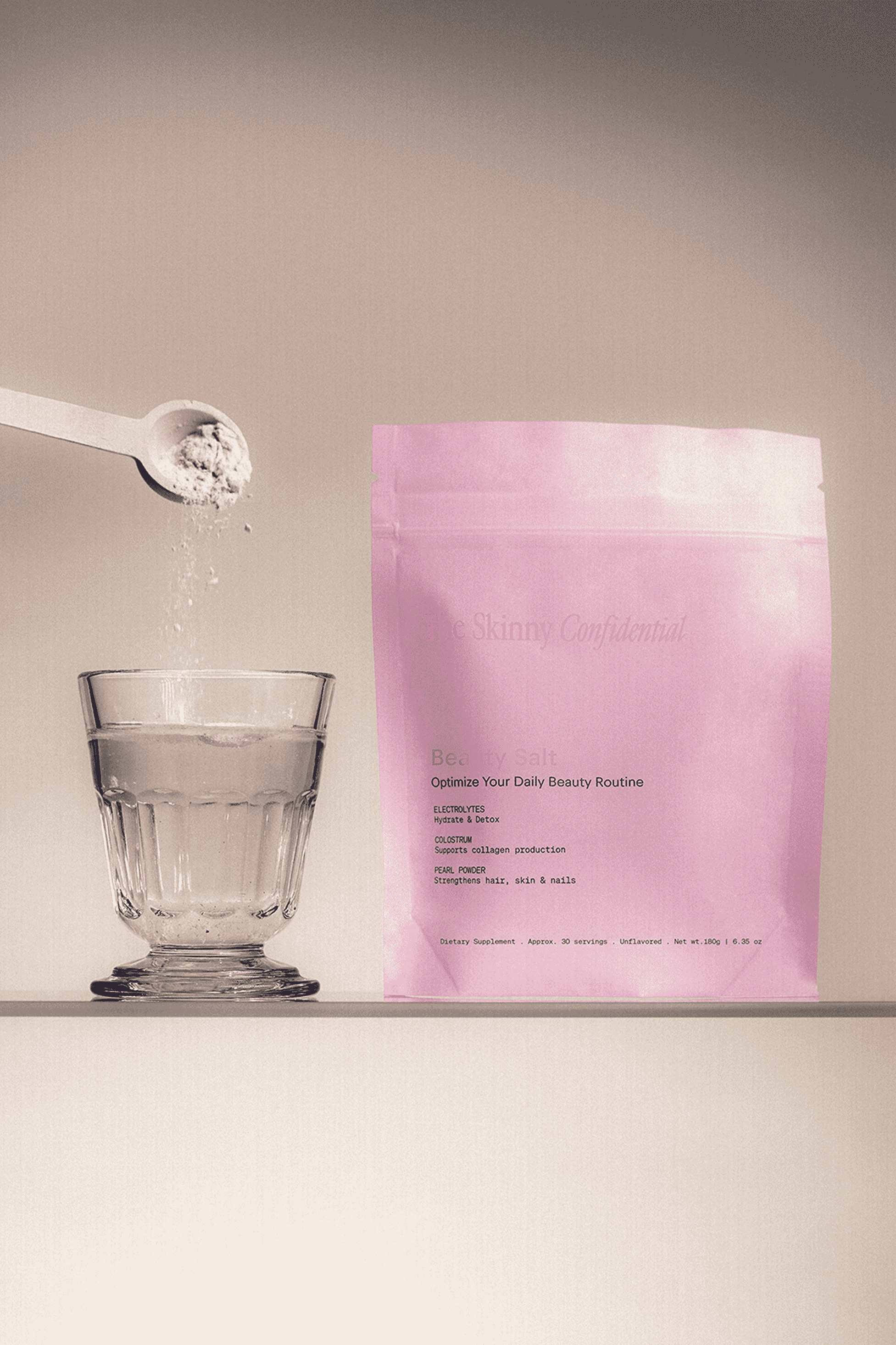The Skinny Confidential Beauty Salt pink packaging with glass and spoon.